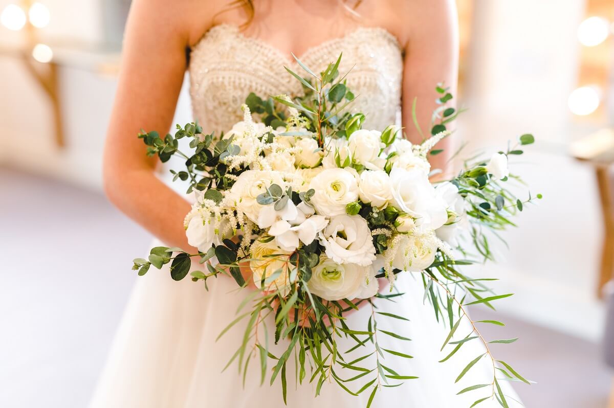 Bride in a white strapless dress holding a bridal bouquet of white flowers